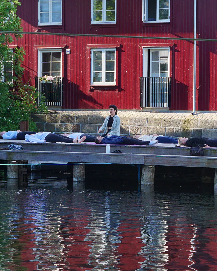 Ioanna sidder med et hvilende yogahold ved vandet