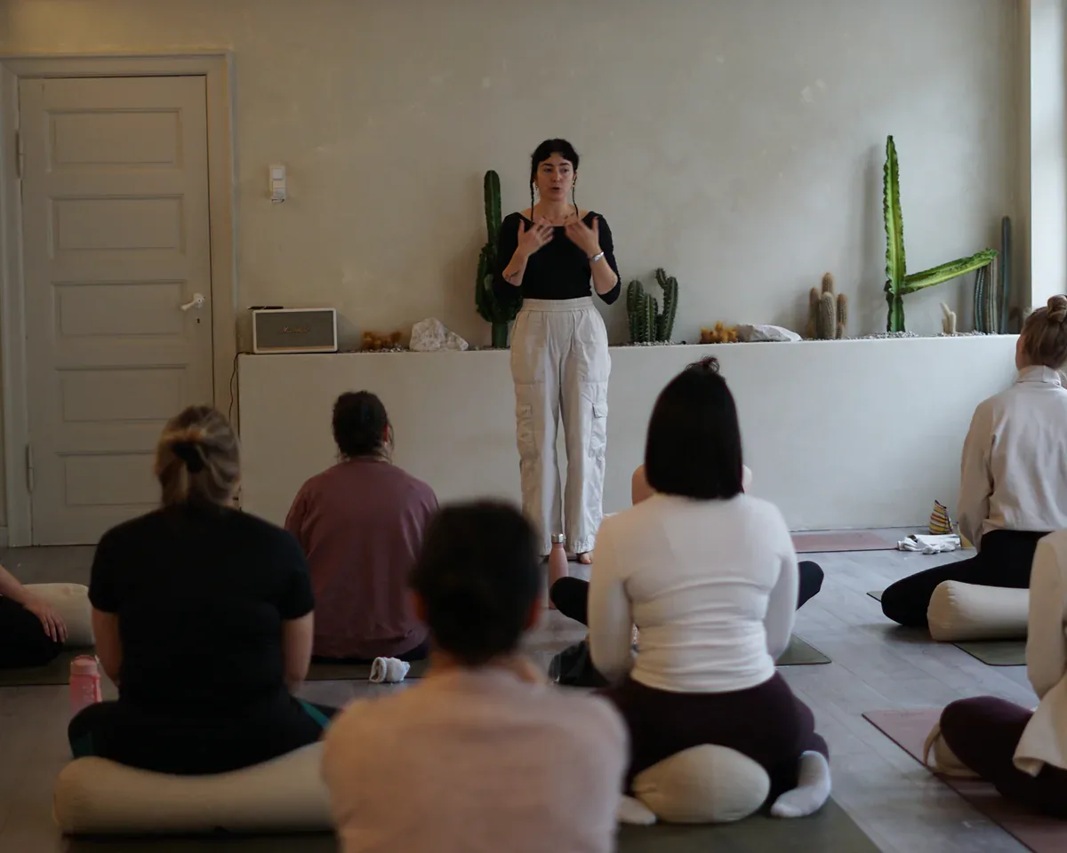 Ioanna guiding a seated yoga class in a bright studio