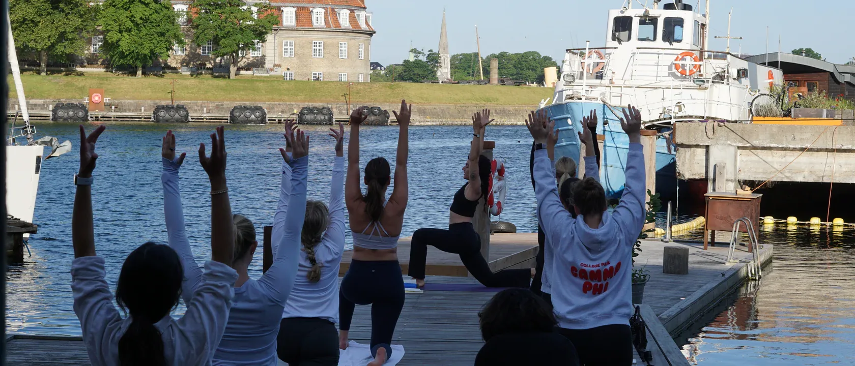 A group raising their arms during an outdoor yoga session by the water